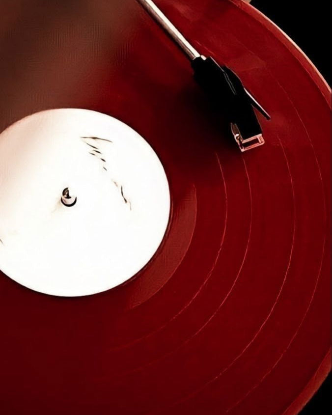 Close-up of a red vinyl record with a needle on a dark background