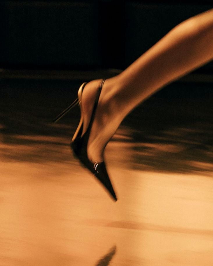 Black high-heeled shoe on a reflective surface with a blurred background