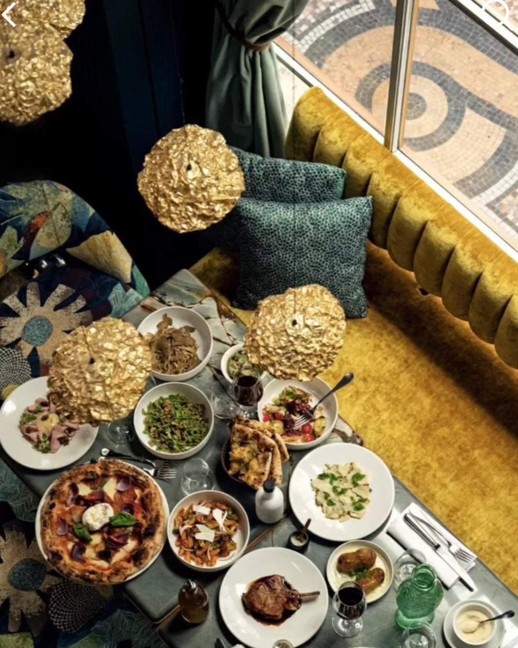 Dining table with various dishes and a yellow sofa with decorative pillows.