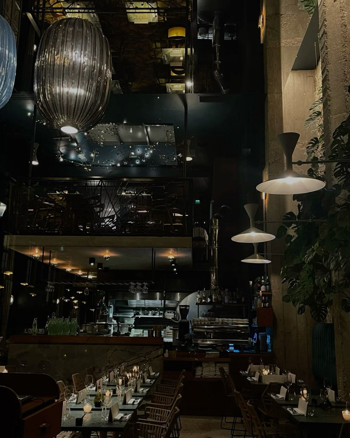 Darkly lit restaurant interior with tables, chairs, and hanging lights.
